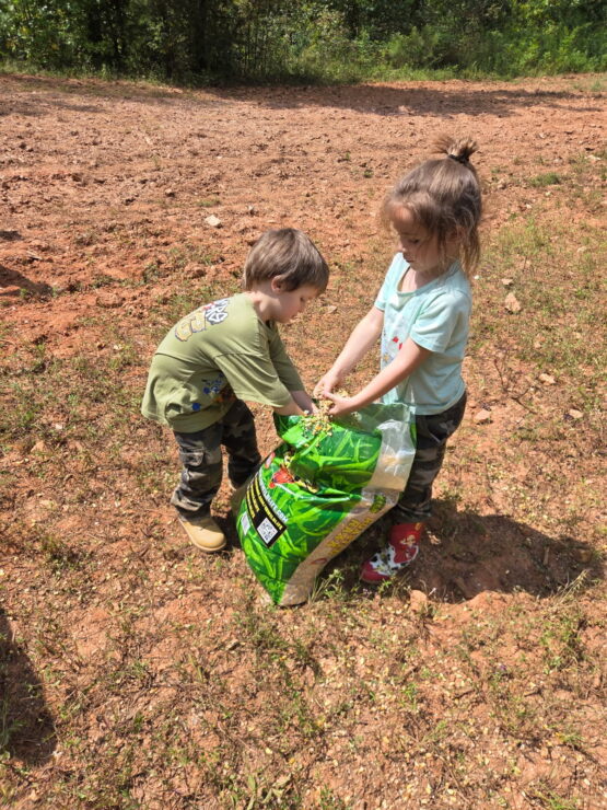 Adorable little girl holding bag of Roasted Raxx, with little boy helping her hold it
